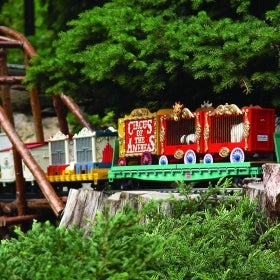 A miniature circus train rides on a wooden trestle. 