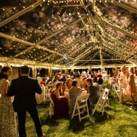 A large party under a clear-top tent.
