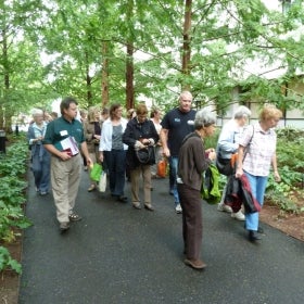 A group of people wearing name tags walk through an outdoor green space.