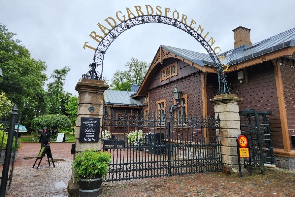 The entrance to a botanical garden with an arched sign that reads, "Trädgårdsföreningen." 