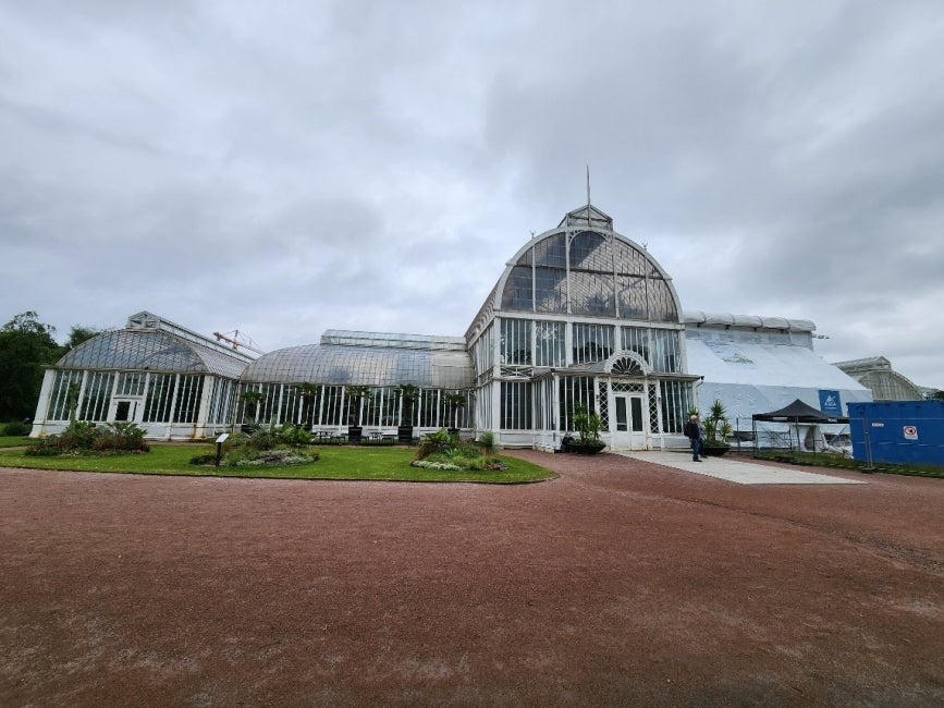 A large green house completely covered in windows. 