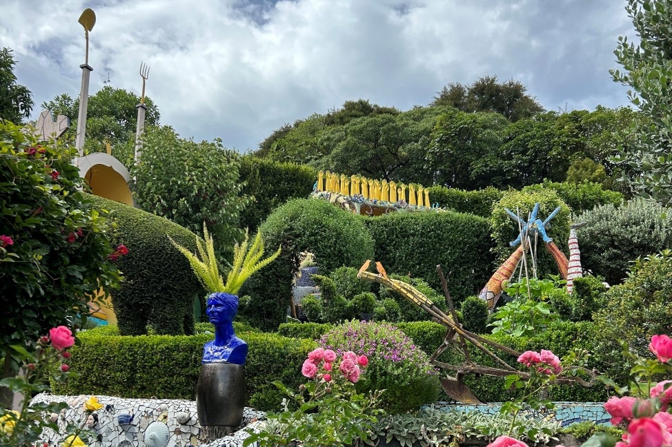 A landscape of topiary and flowers in bloom with large, colorful sculptures throughout. 