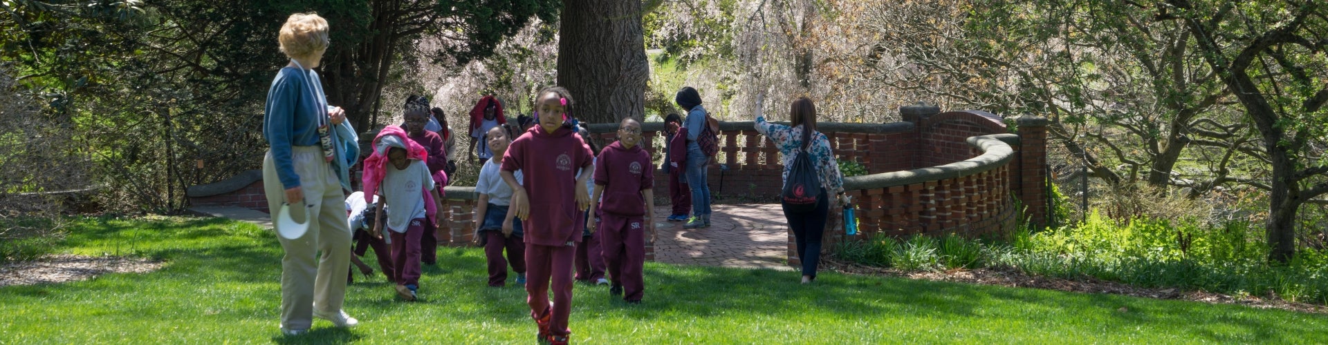 A group of students are led on a tour of a public garden in spring. 