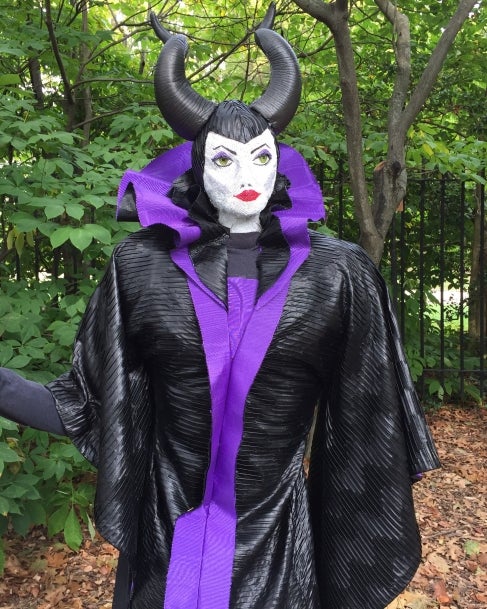 A scarecrow made to look like the Disney villian Malificent, with black horns and a purple and black dress. 