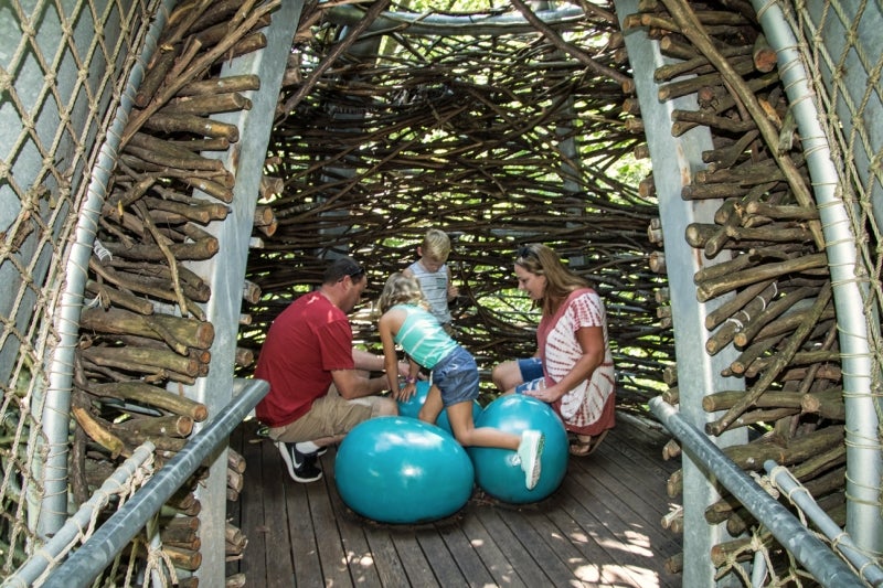 A family in an oversized bird's next with large blue eggs. 