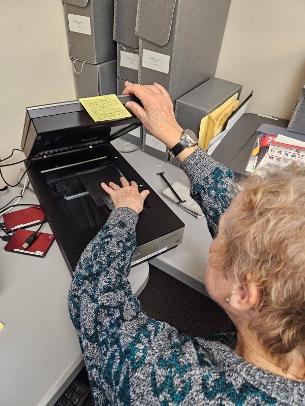 A woman uses a film scanner to digitize historical negatives.